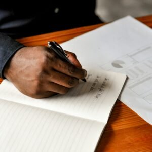 a hand holding a pen over a notebook